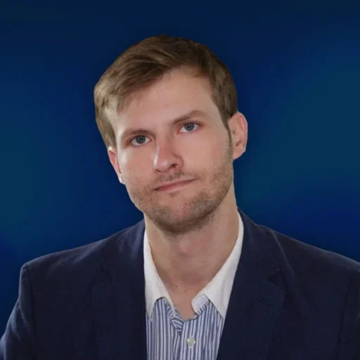 Person in suit against blue background.