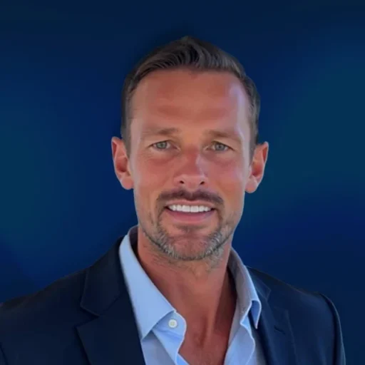 Smiling man in suit, blue background.