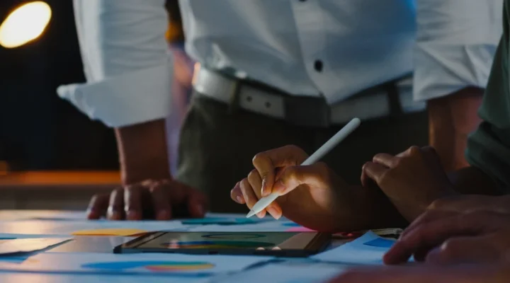 A team working together on a digital marketing plan using a tablet and other materials spread across the table.