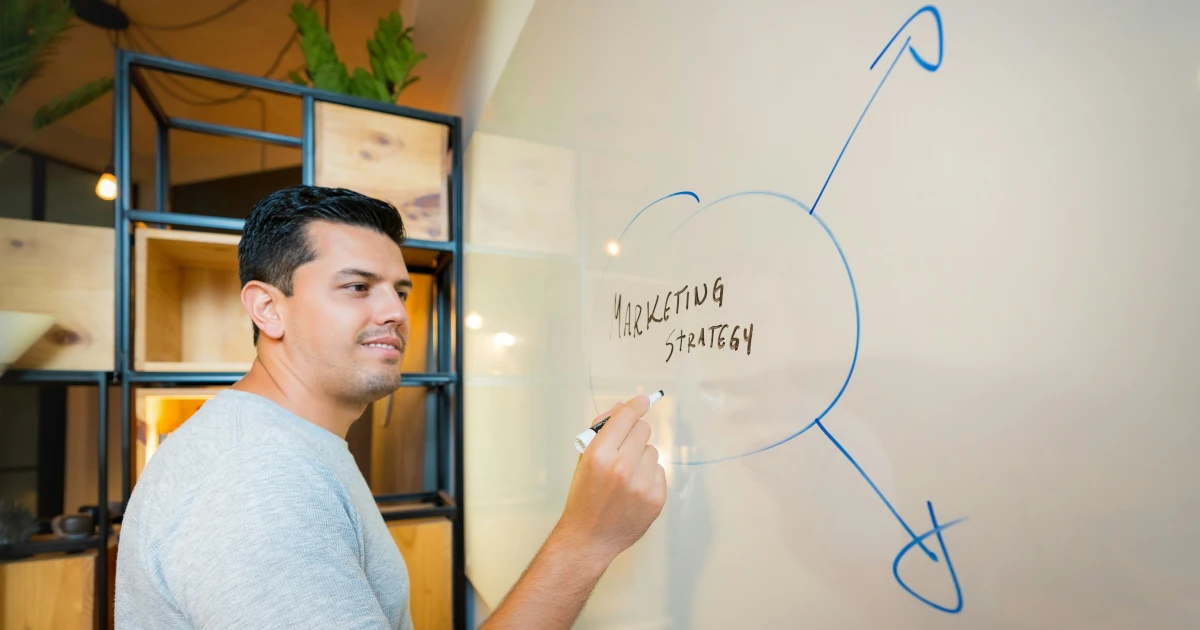 A founder writing 'Marketing Strategy' on a whiteboard with arrows branching out to channel decisions